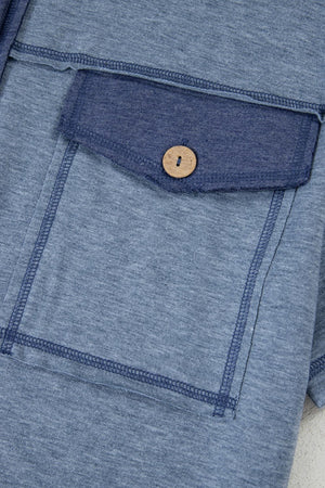 Denim-trimmed utility jumpsuit in dusty blue with a buttoned chest pocket and contrast stitching.
