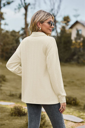 Textured knit polo shirt in ivory with a subtle cable pattern and buttoned collar.