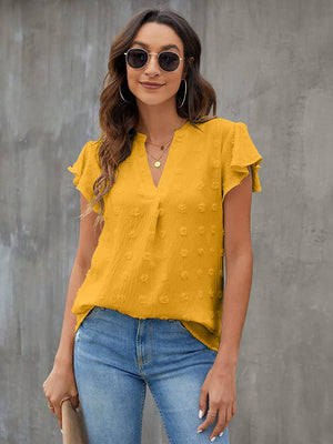 Textured voile blouse in gold with flutter sleeves and V-neck, styled with jeans.