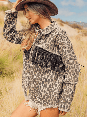 Leopard print denim jacket with collared neck, frayed details, and black fringe embellishment.