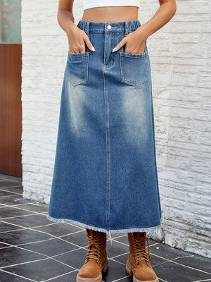Faded denim midi skirt in dusty blue with frayed hem and front pockets.