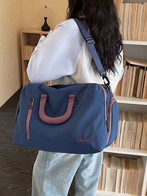 Blue travel bag with pink accents and adjustable strap, perfect for carry-on.