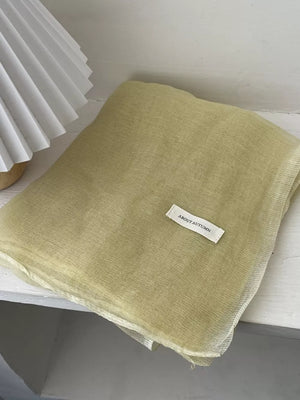 Delicate sheer polyester scarf in creamy yellow with a subtle crinkle texture.