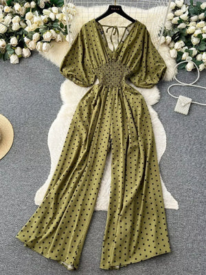 Army green polka dot smocked wide-leg romper with V-neck and tie back.