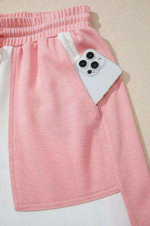 Pink and cream color block cotton lounge set shorts with side pocket holding a phone.