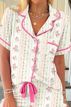 Pajama set in ivory with pink floral print, button-up top with short sleeves and a bow detail.