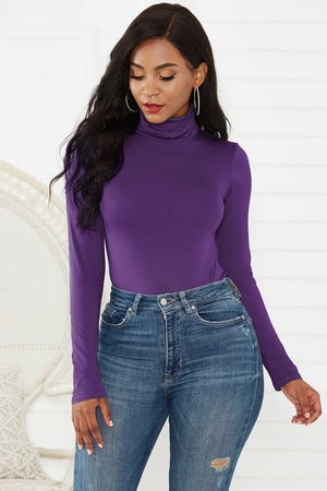 Purple turtleneck thong bodysuit with long sleeves, styled with high-waisted jeans.