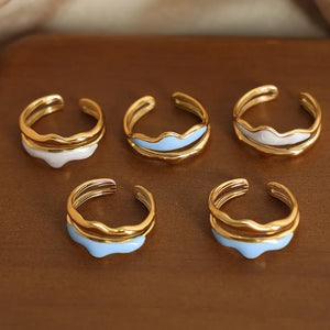 Gold tone rings with sculpted wave enamel in white and light blue.