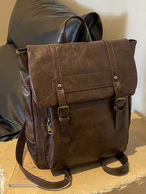 Brown pu leather flap backpack with brass hardware and adjustable straps.