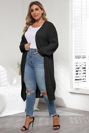Black oversized knit maxi cardigan with V-neck and long sleeves, styled with jeans.