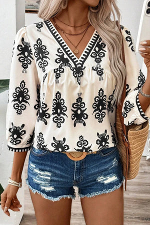 Ivory blouse with black embroidered pattern, V-neck, 3/4 sleeves, and contrast trim.