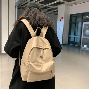 Khaki canvas school backpack with dual pockets and zipper closure.