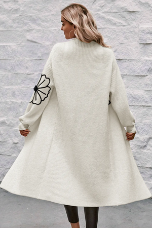 Ivory acrylic maxi cardigan with black floral appliqué on sleeves, open front, long sleeves.