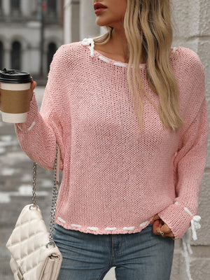 Dusty pink knit sweater with white stitched trim and bow details on sleeves and neckline.