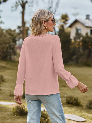 Blush pink textured blouse with lace trim neckline and bell sleeves.