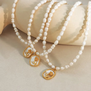 Gold baroque pearl necklace with floral medallion charms and delicate rose detail.