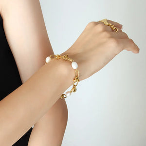 Gold knot and pearl link bracelet with oval pearls on a chain.