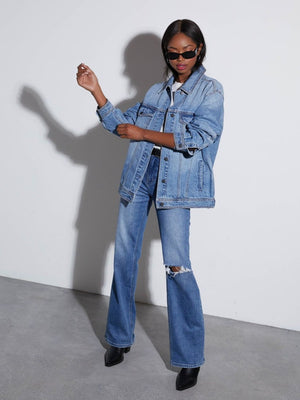Denim trucker jacket in medium wash with collar and buttons, styled with ripped flare jeans.
