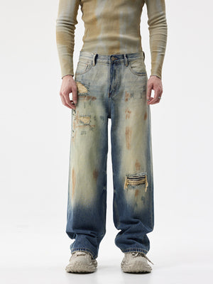 Men's distressed wide-leg jeans in blue denim with ripped details and faded wash.