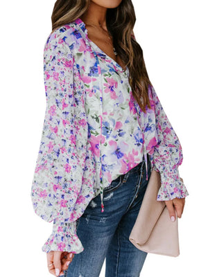 Vibrant floral print blouse with tie detail, long balloon sleeves, and ruffled cuffs.