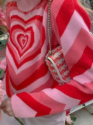 Heartbeat Stripe Mock Neck Knit sweater in pink and red with a chevron stripe pattern.