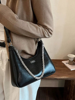 Black patent leather crossbody bag with silver chain detail and logo