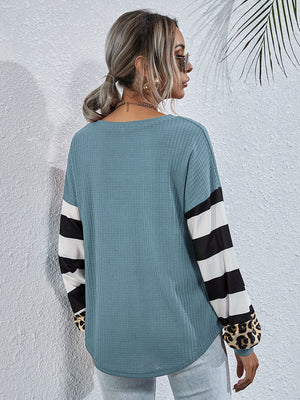 Sky blue waffle knit top with striped and leopard print sleeves.