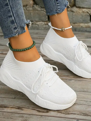 White knit runner sneakers with sculpted sole and white laces.