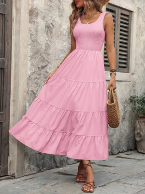 Pink smocked bodice tiered maxi dress with scoop neck and sleeveless design.