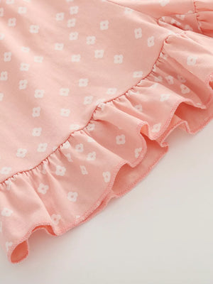 Pink cotton tee with white floral print and ruffled hem detail.