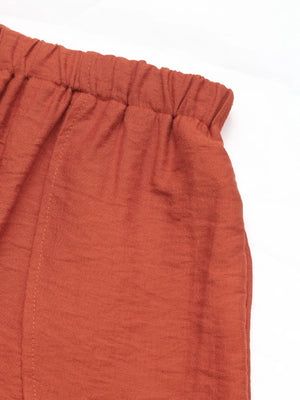 Terracotta linen lounge pants with elastic waistband and visible stitching detail.