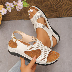 Chic cutout wedge sandals in white with adjustable ankle strap and perforated detail.