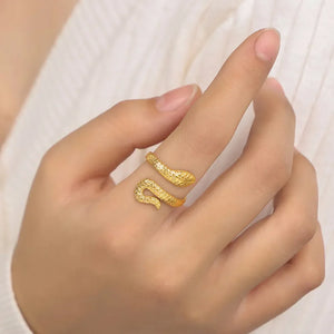 Gold serpent wrap ring with textured scales, worn on a finger.