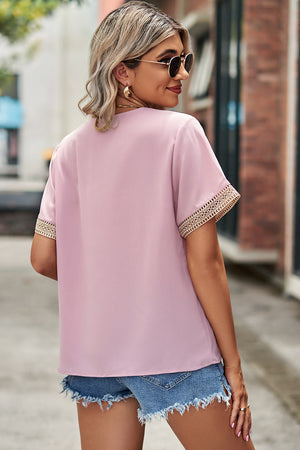 Blush pink V-neck blouse with lace trim on short sleeves.