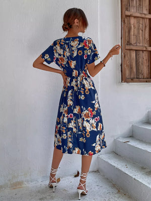 Blue midi dress with vibrant floral pattern, short sleeves, cinched waist, and a-line skirt.