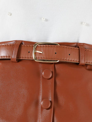 Toddler white pearl-embellished top with brown faux leather skirt, belt, and button detail.