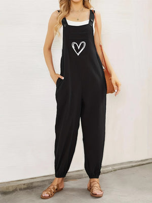 Black cotton overalls jumpsuit with white heart pocket detail, adjustable straps, and cuffed ankles.