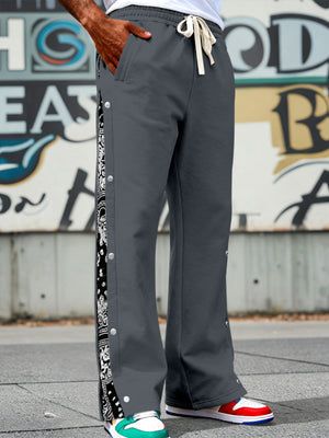 Men's dark gray sweatpants with drawstring and side snaps, featuring a paisley stripe detail.