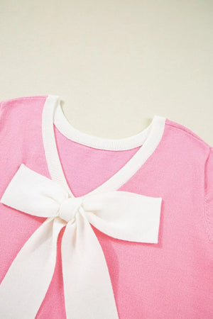 Pink knit top with white contrast trim and a large white bow detail on the front.