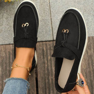 Black decorative strap flat slip-ons with gold hardware detail.
