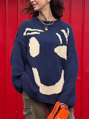 Dark blue knit sweater with abstract cream graphic face pattern, crew neck, long sleeves.