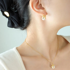 Gold pearl bow drop earrings with 18K gold plating.
