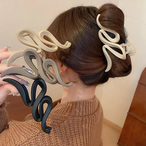 Sculptural hair claw clips in black, tan, and dust storm acrylic with serpentine design.