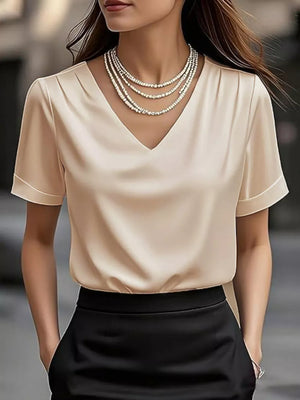 Apricot satin V-neck shirt with cuffed sleeves and draped neckline.