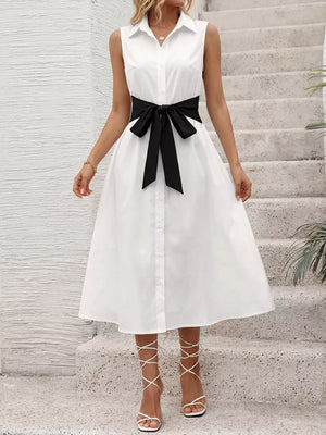 White midi shirt dress with black bow tie belt, button front, and sleeveless design.