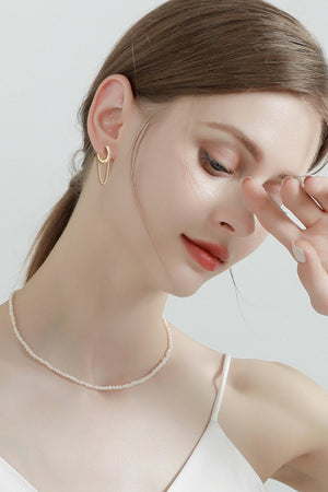 Gold dangling chain pavé huggie earrings with delicate crystal accents.
