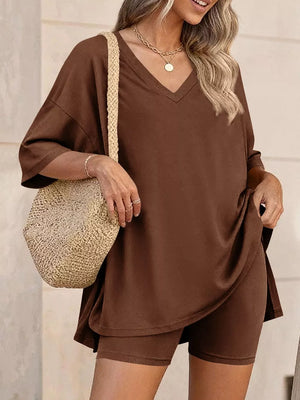 Brown V-neck two-piece set with relaxed fit top and bike shorts, styled with a straw bag.