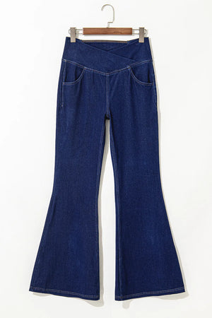 Medium wash denim flare trousers with asymmetric crossover waist and front pockets.
