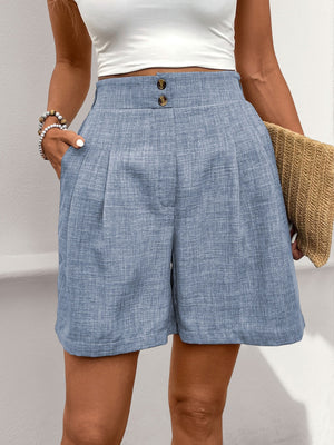 Light blue linen shorts with high waist, pleats, and button detail.