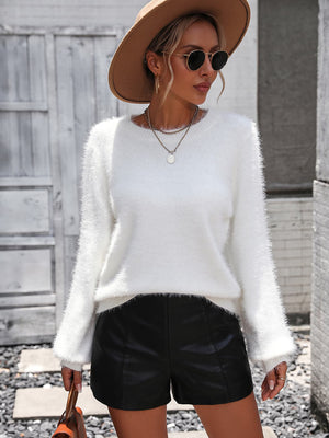 White fluffy knit sweater with crew neck and long sleeves, styled with black shorts.